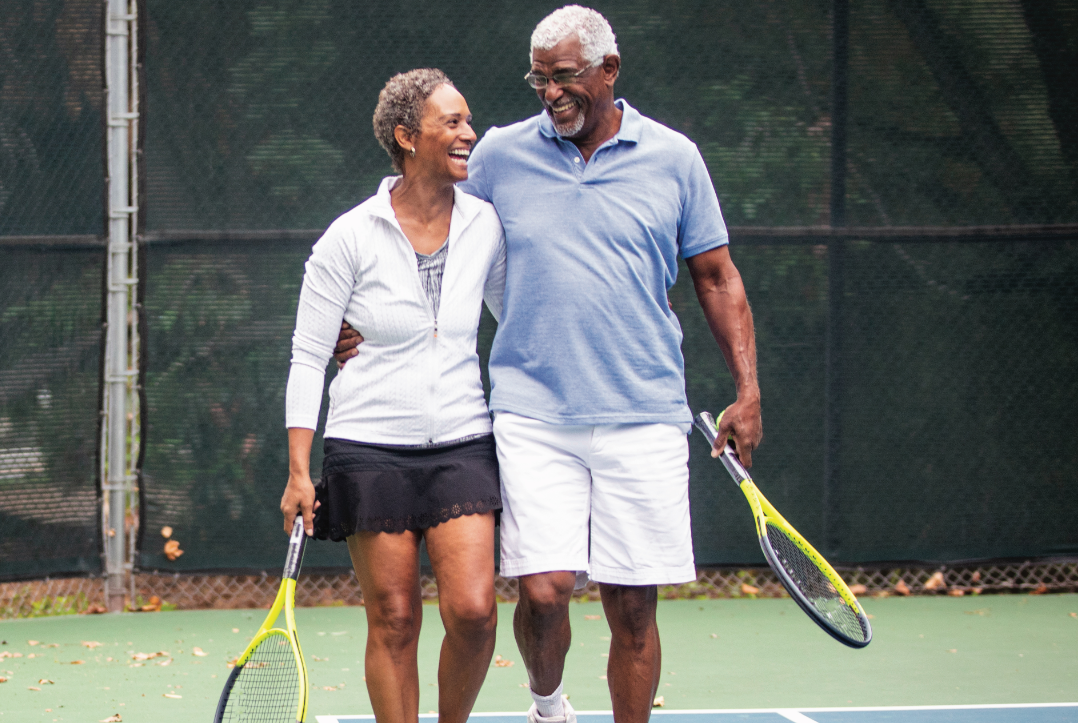 Two people walk together on the tennis court.