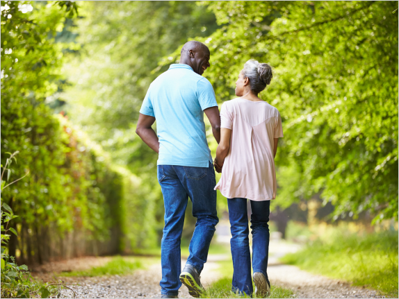 Two people walking, holding hands, outdoors.