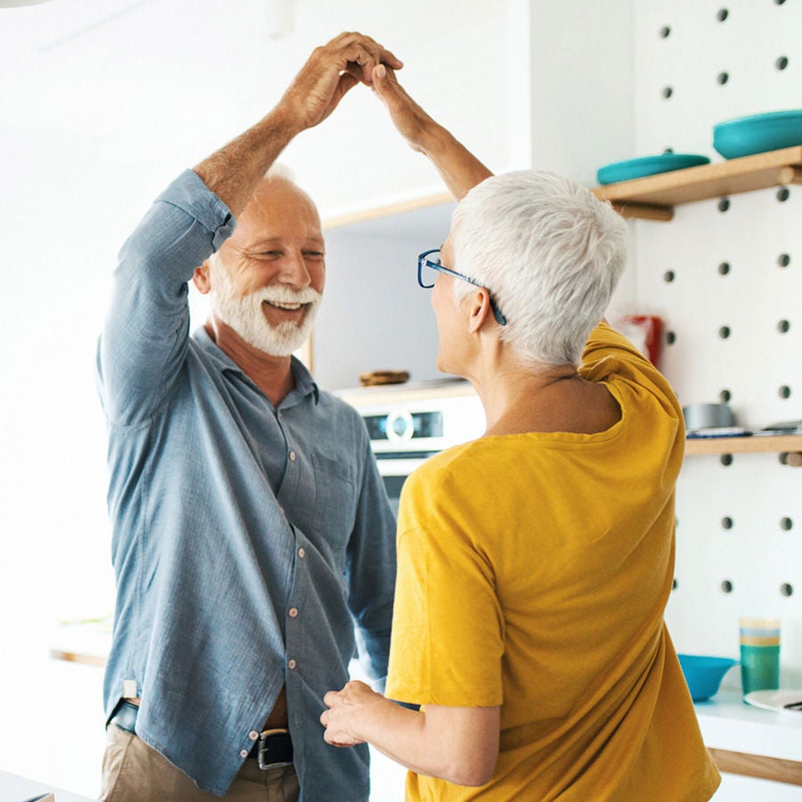 A happy couple dance in the kitchen.