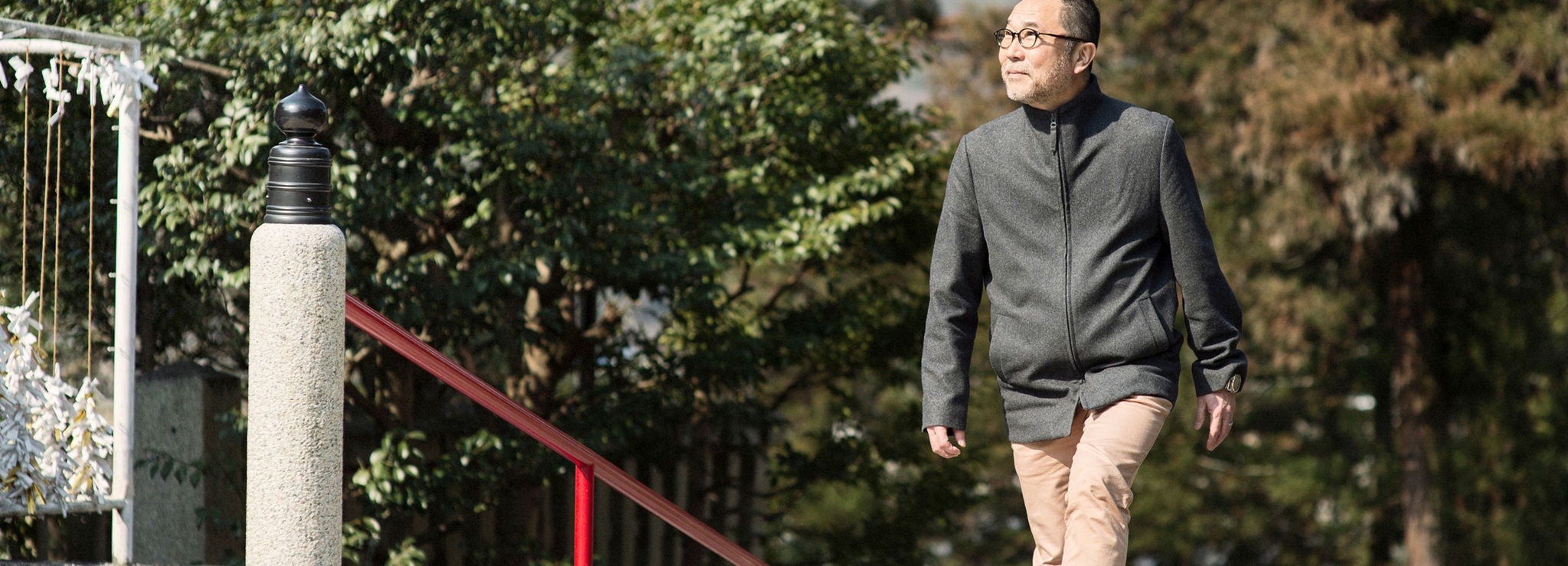 A person grins as they walk outside in the sunshine.
