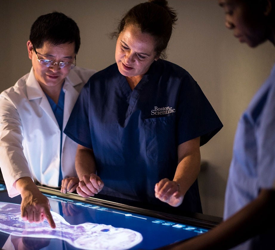 Two medical professionals analyze a digital display of a patient's spine.