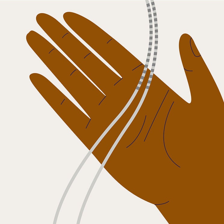 A hand holds two gray wires, also known as leads. 