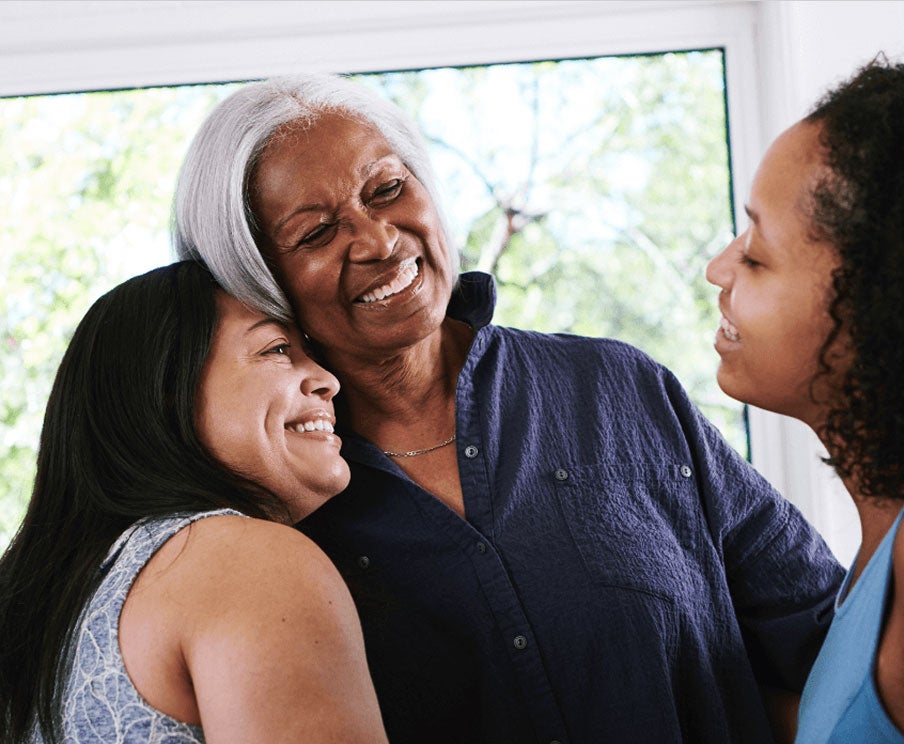 Three people smile as they embrace each other fondly.