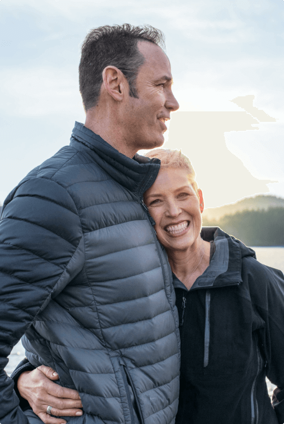 Man and woman standing in front of a lake.