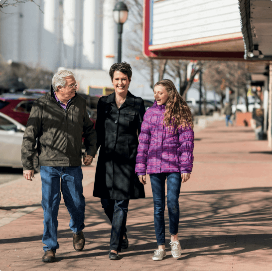 Karen walking with her husband and daughter on a city sidewalk.