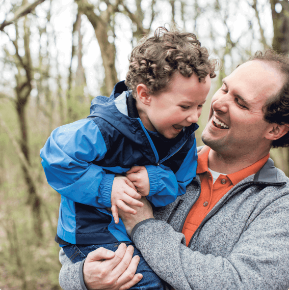 Chris holding his son in the woods.