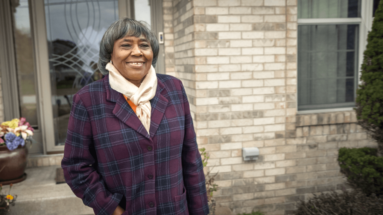 Shirley standing in front of her home.