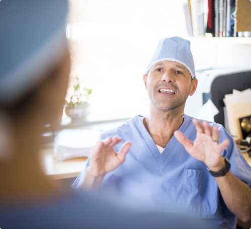 Male doctor in scrubs talking to another doctor.