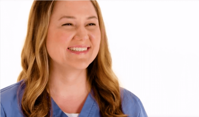 Woman in blue scrubs smiling.