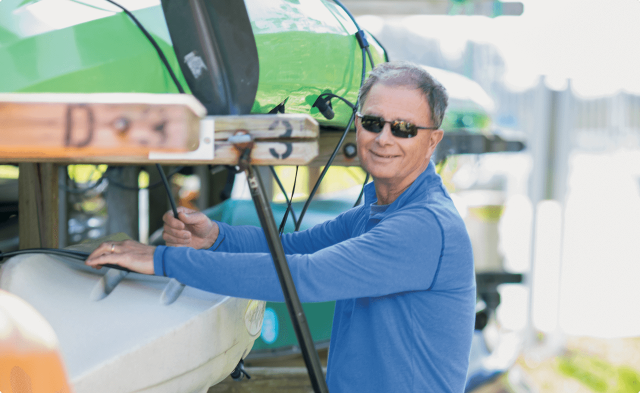 Man in a blue shirt tying down a kayak.