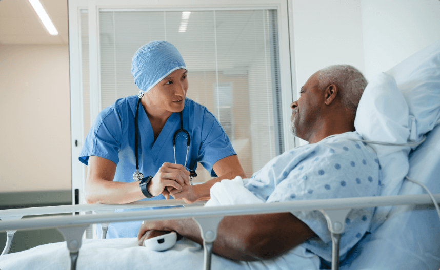 Man in a hospital bed talking to a doctor.