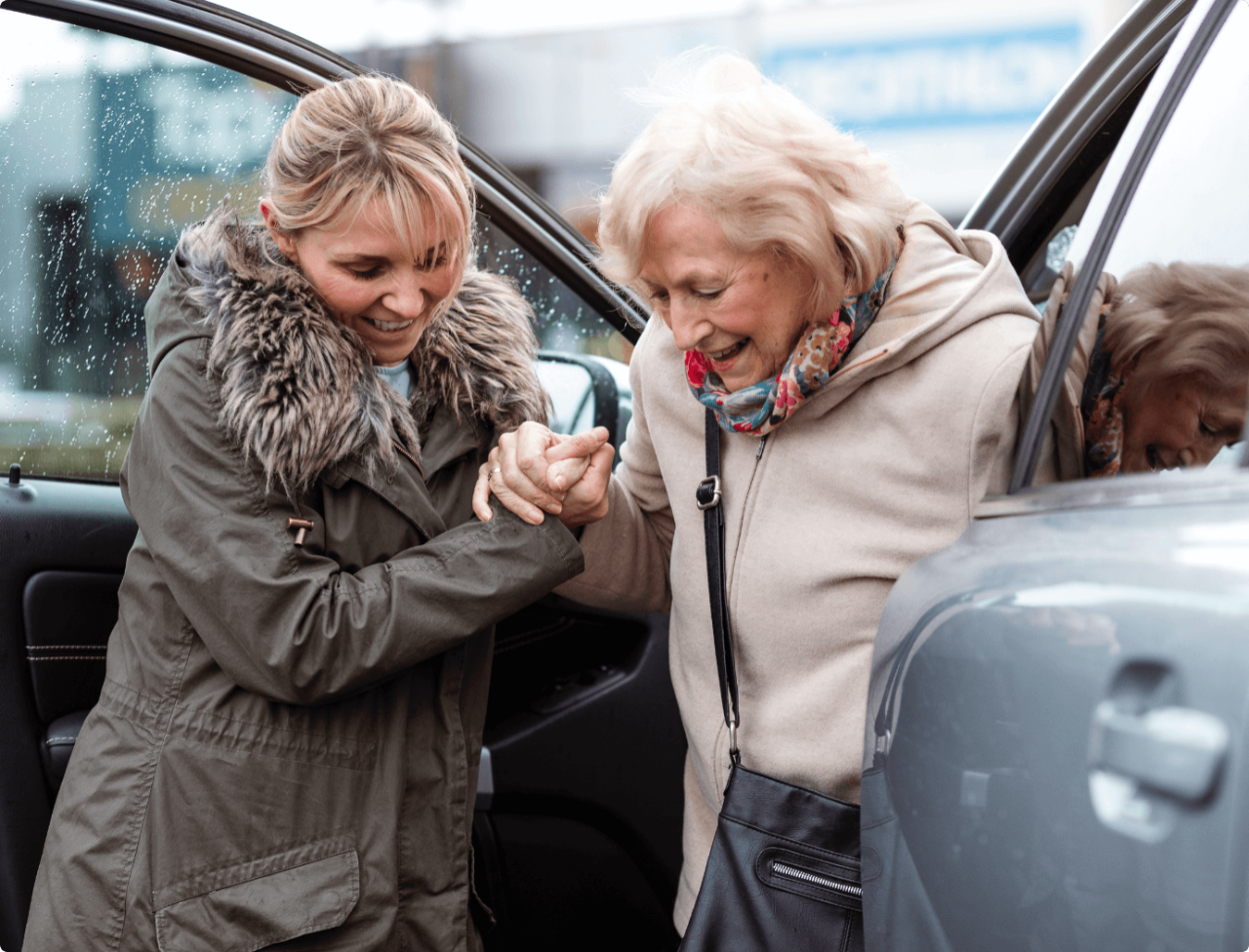 A woman helping another woman to get out of a car.