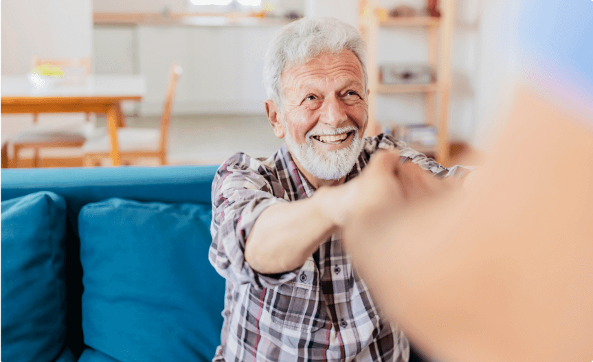 Caregiver helping a man off a couch.