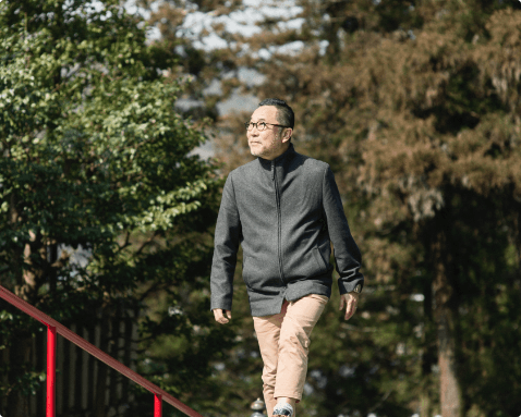 A man walking across a bridge in a wooded area.