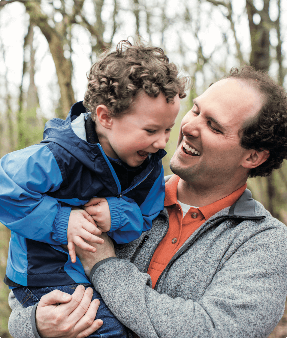 Chris holding his son in the woods.