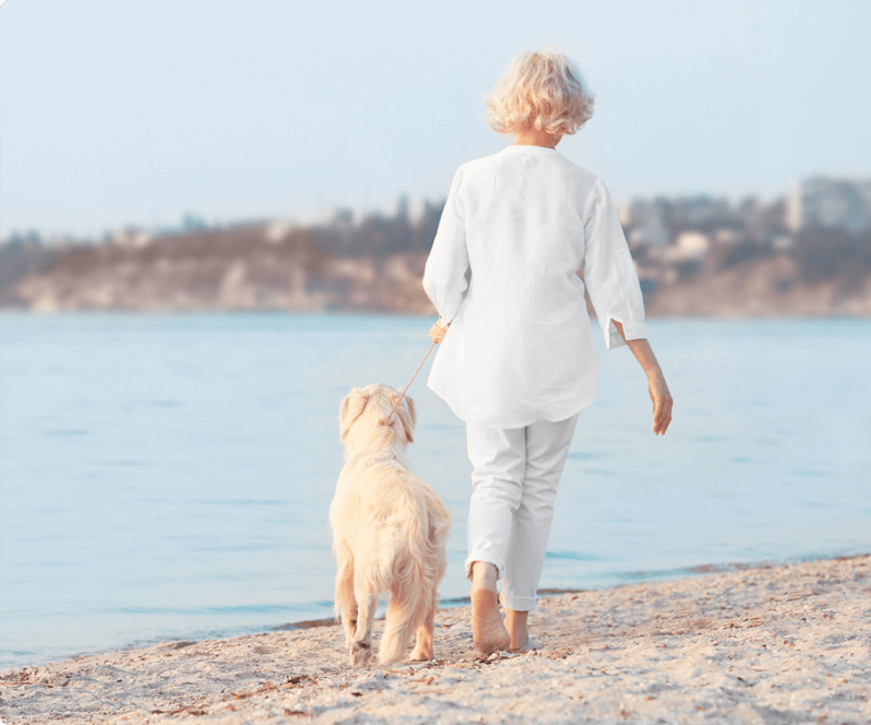 Spinal Cord Stimulation patient Roxanne walking her dog on the beach.