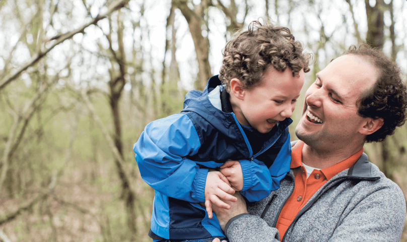 Chris holding his son in the woods.