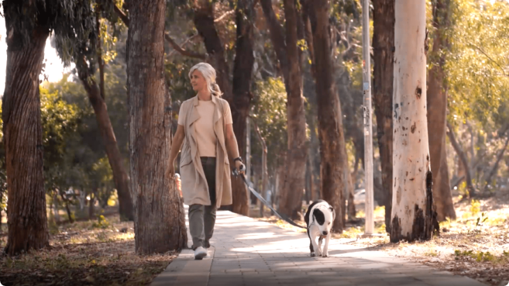 Woman walking dog on a sunny day.