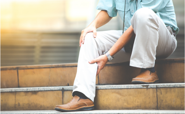 Mature man holds lower leg in pain.