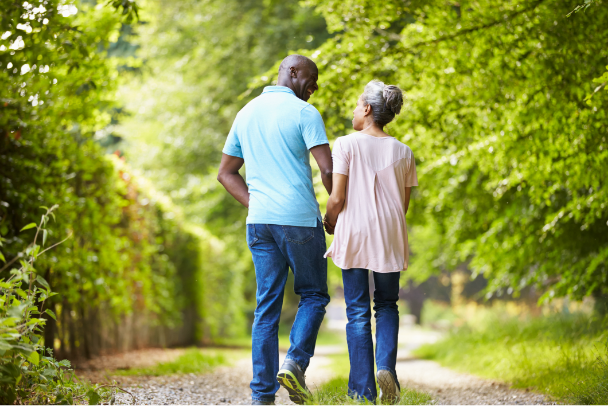Man walks with mature woman outdoors.