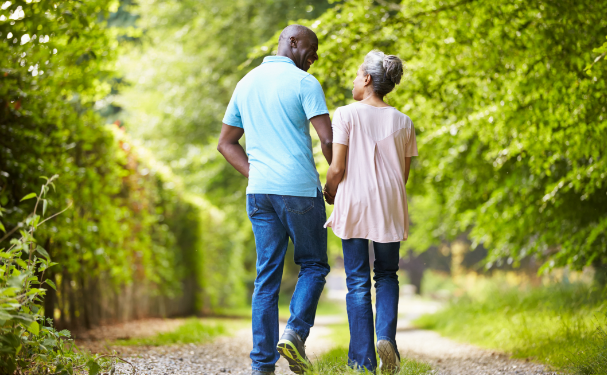 Man walks with mature woman outdoors.