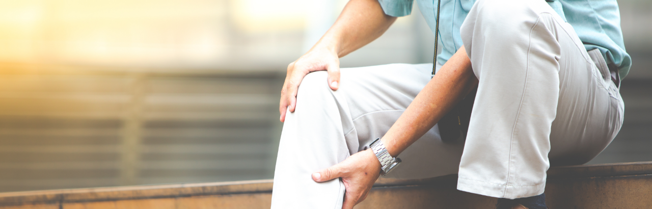 Mature man holds lower leg in pain.