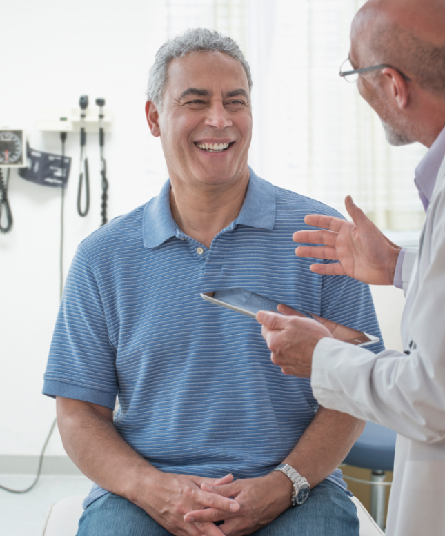 A doctor holding a tablet talking to a patient.