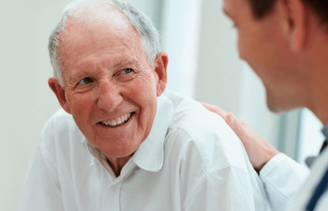 A doctor standing with his hand on the shoulder of a patient.