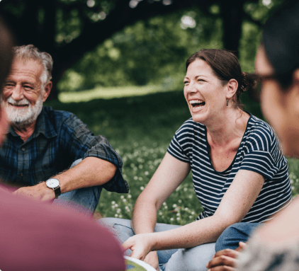 A group of people sitting in the grass laughing.