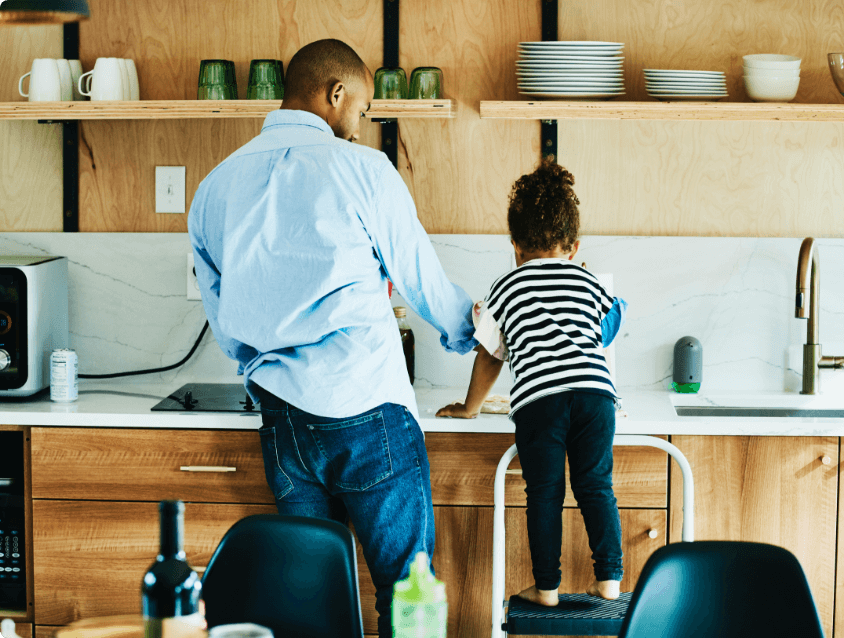 Father and daughter washing dishes in a kitchen sink.