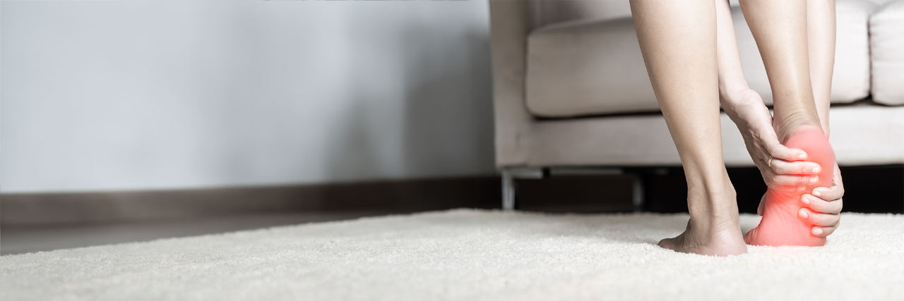 Person holding right foot that is shaded in red to communicate pain.