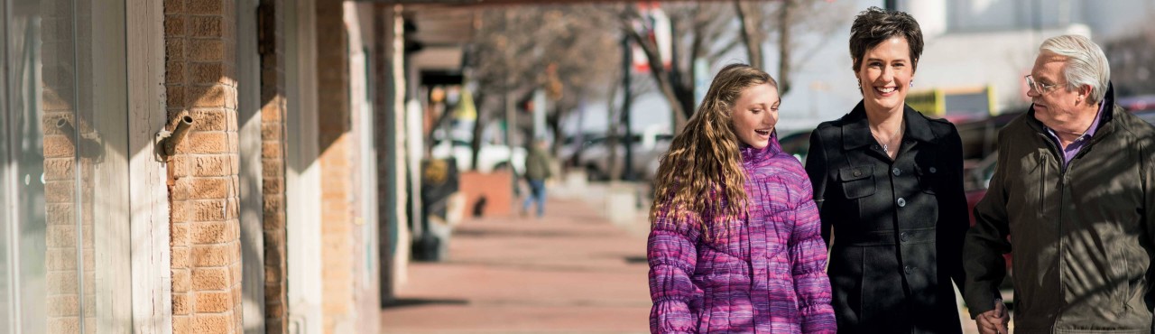 SCS patient Karen walking outdoors with daughter and husband.