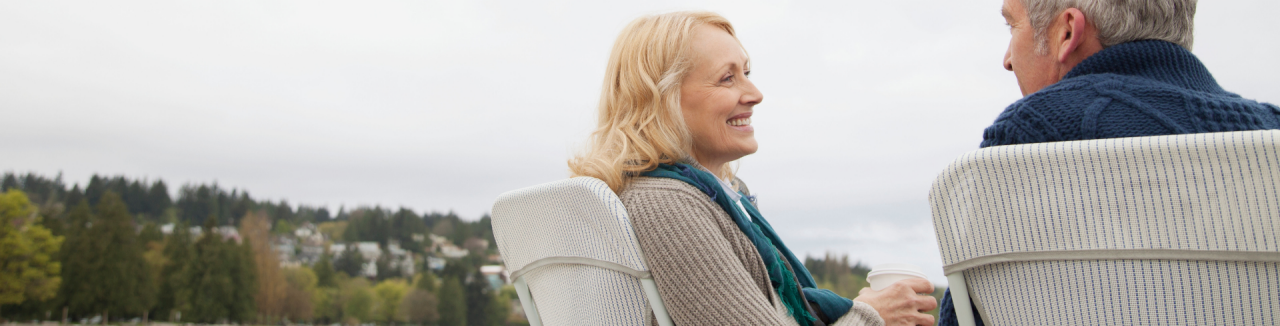 middle-aged couple relaxing with coffee at lakeshore