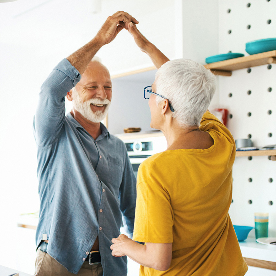 A happy couple dance in the kitchen.