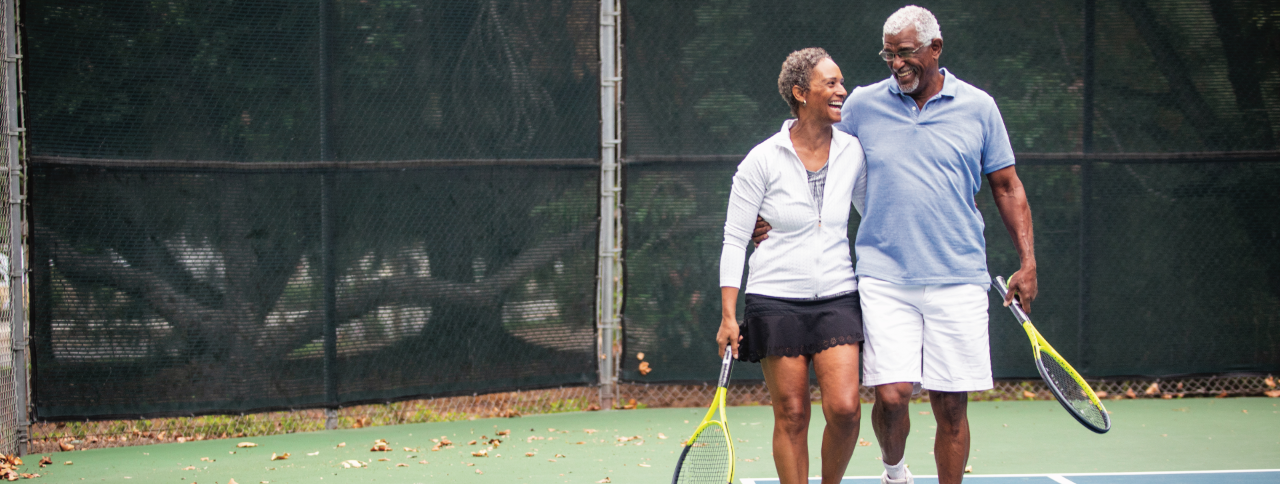 Two people walk together on the tennis court.