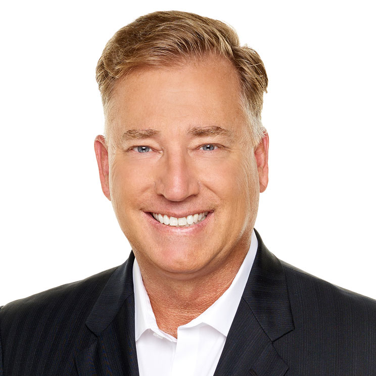 Scott B. smiles. With light brown hair and a dark suit with a white shirt.