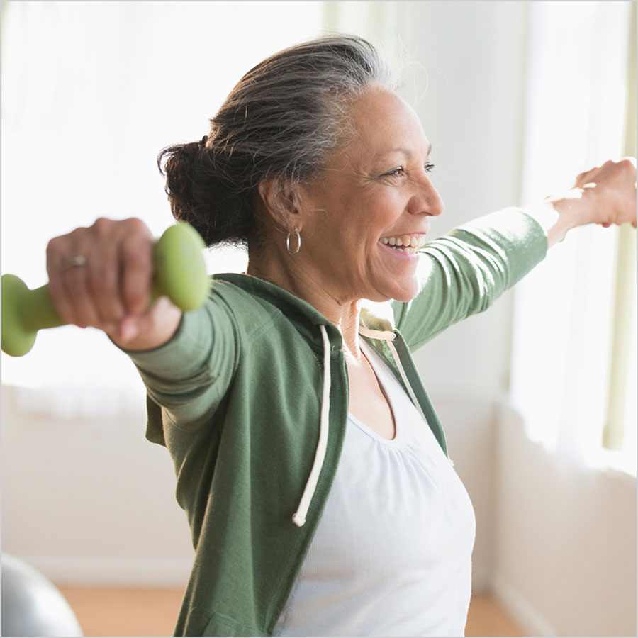 A person laughs and lifts small weights in both hands.