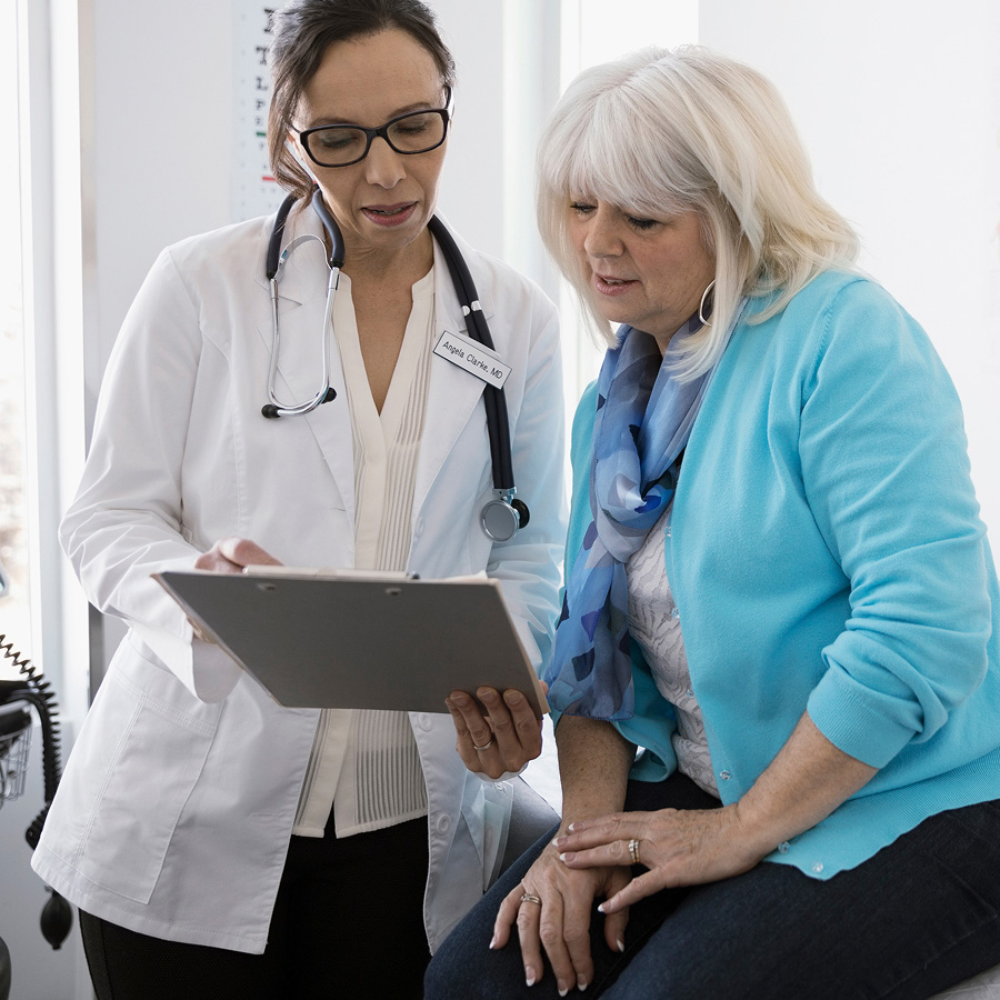A healthcare professional shows a patient information on a clipboard.