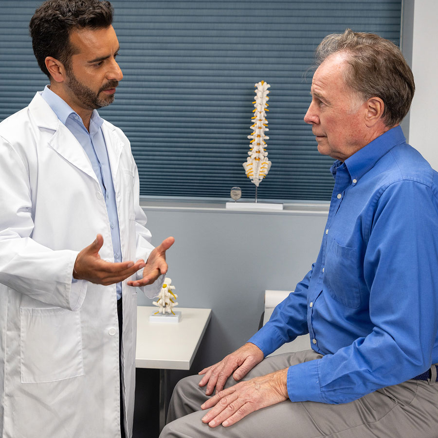 A doctor talks to a seated patient in an office.